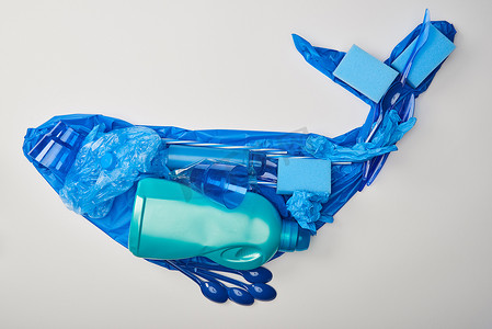 用橡胶手套、一次性塑料餐具、袋子、海绵和白色瓶子制成的鲸鱼人影的顶视图