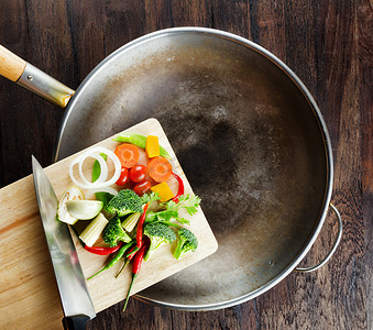 新鲜蔬菜在切菜板上落在锅中。co