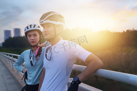 骑行的青年情侣站在桥上看风景