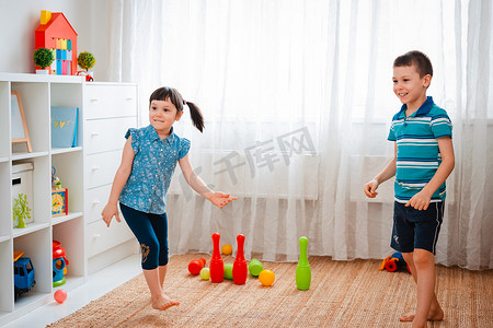 土生土长的男孩和女孩在儿童游戏室里玩耍，扔球。互动的概念兄弟姐妹，交流，相互游戏，隔离，自我隔离的家，兄妹.
