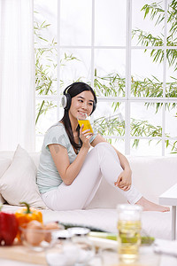 年轻女人坐在沙发上喝果汁