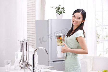 一个年轻女人在厨房手拿榨汁机