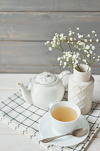绿茶在一个杯子旁边的茶壶和一个花瓶与婴儿的呼吸在木制背景