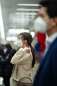 戴口罩的年轻女人站在地铁站台上