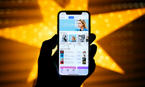 巴黎, 法国-2017年11月10日: 男子手持新的苹果 iphone X 10 显示与黄色星散背景以最佳的星期 itunes Louane 图 