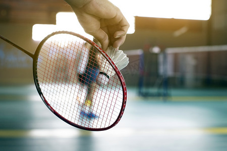羽毛球手将球拍和白色奶油羽毛球放在网前，然后发到球场的另一边.