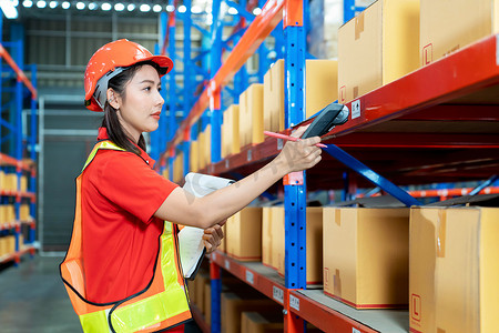 Female worker with protective vest and scanner, holds document, standing at warehouse of freight forwarding company, scanning qr code for delivery 