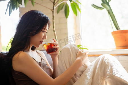 吊带摄影照片_年轻女人在家喝茶休息