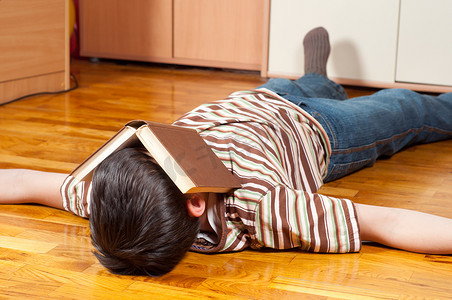 十几岁的男孩睡在地板上在读取时