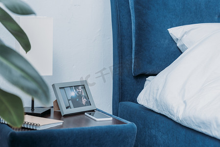 在床头柜上的照片框的选择性焦点与人, 笔记本电脑和智能手机的图片