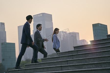 由三位亚洲企业行政人员组成的团队在市中心金融区行走