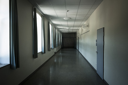 9点摄影照片_黑暗的学校弯曲的走廊，有丑陋的绿色窗帘和黄色的墙壁，时钟显示上午9点20分.