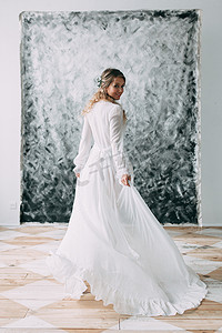 2018春天摄影照片_美丽的年轻新娘在闺房的衣服上的画布背景与油漆。婚礼的趋势和想法 2018, 春天的灵感。婚礼在演播室