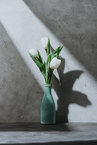 蓝色花瓶的白色郁金香花在混凝土表面与阴影