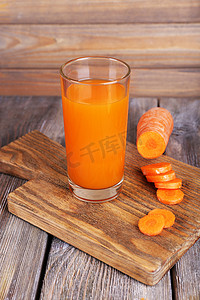 杯胡萝卜汁和新鲜胡萝卜在木制的桌子上木板墙背景上砧板上