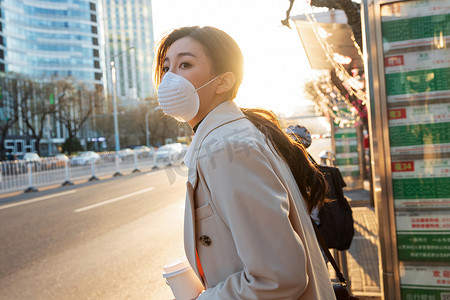 戴口罩的图片摄影照片_戴口罩的年轻女人站在公交车站