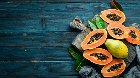 热带水果，甜木瓜，蓝色木制背景的生素食食品。顶部视图。文本的可用空间.