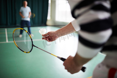 高级感灰纯色摄影照片_高级羽毛球运动员拿着羽毛球, 同时要把它传递过去, 用球拍交配