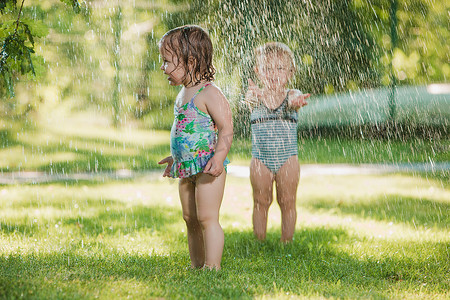 这两个小宝贝女孩子在玩花园洒水.