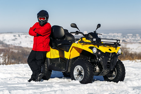 年轻的司机坐在ATV四轮驱动的自行车上，站在大雪中，有着很深的轮轨。摩托冬季运动.