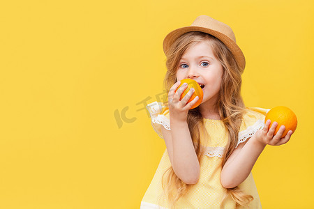 一个金发碧眼的小女孩手里拿着橙子. 