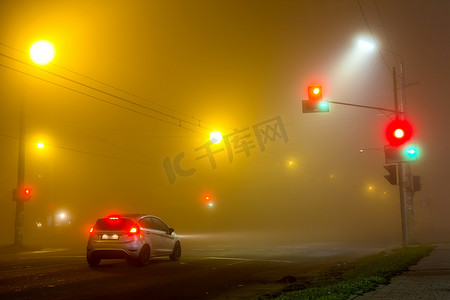 在空旷的道路上的浓雾与孤独的汽车和交通灯 