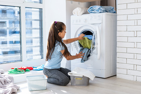 漂亮的小女孩小助手在家里洗衣服的时候玩得很开心.