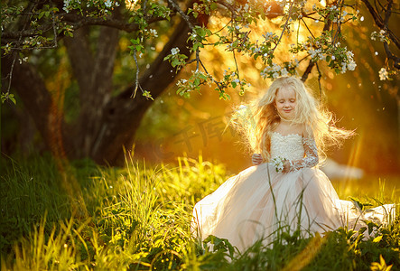 异人之下摄影照片_小女孩在白色礼服站立在苹果树之下在日落和笑