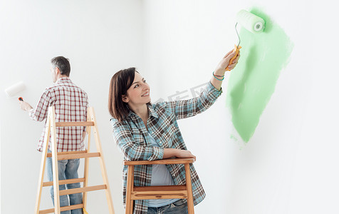 对夫妇装修他们的家和粉刷墙壁和油漆滚筒