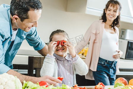 幸福的家庭, 小孩子在厨房里看着妈妈和孕妇的时候, 把辣椒片应用到眼睛上