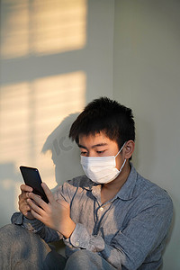 手机病毒摄影照片_戴口罩的男孩看手机