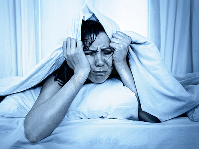 睡眠障碍摄影照片_年轻女子在床上痛苦强调失眠和睡眠障碍