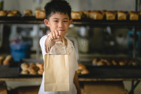 小男孩拿摄影照片_小男孩拿着袋子纸背景面包店