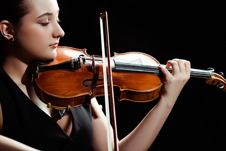 在用黑色孤立的小提琴演奏交响乐的迷人的女音乐家