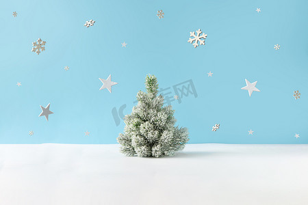 有白雪的圣诞树和明亮蓝色背景的雪花群星的创意布局。 最少的冬季自然假期场景. 
