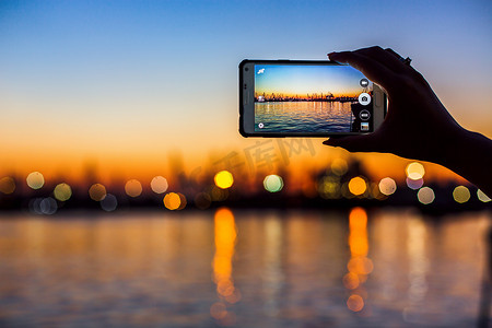 旅游拍照的海港口与移动设备在日落时的