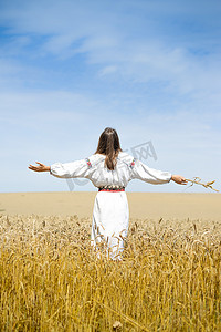 Picture of female in traditional dress standing hands up to sky relaxing in wheat field on summer day background outdoors 