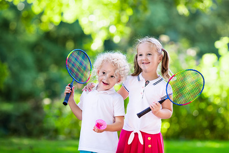 小孩打羽毛球或网球在室外篮球场