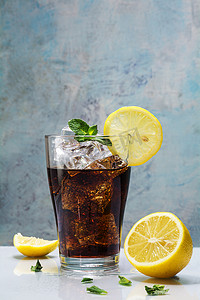 glass of cola or coke with ice cubes, lemon slices and peppermin