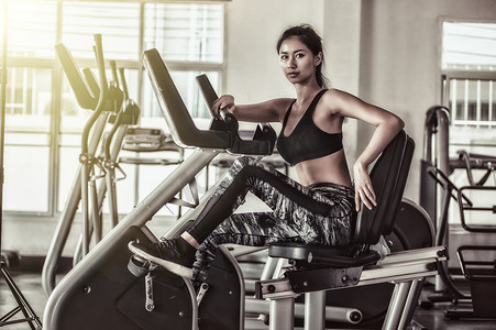 大力神纹摄影照片_亚洲女子在健身房大力骑健身车