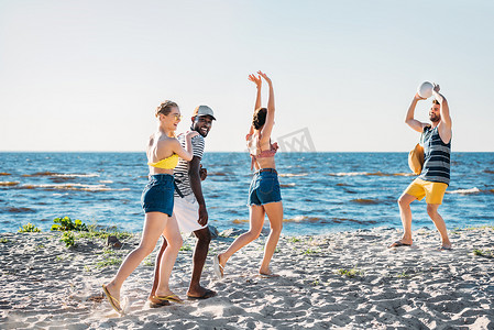 在沙滩上打排球的年轻多民族朋友 