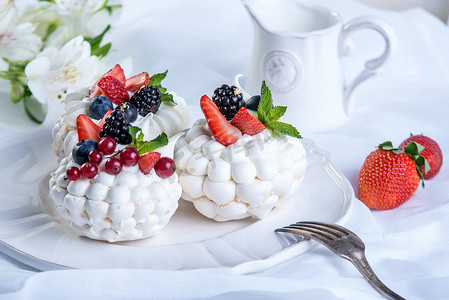 精致的白色蛋白甜饼与新鲜的浆果在盘子里。甜点帕夫洛娃特写。白色背景。喜庆的婚礼蛋糕.
