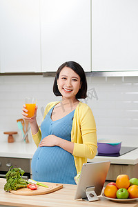 怀孕妇女，厨房里有一杯橙汁
