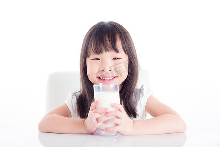 女孩坐在和拿着一杯牛奶在白色