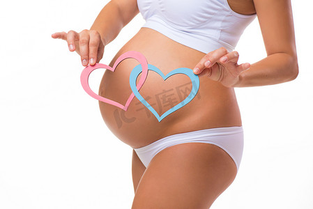 boy摄影照片_Pregnant belly with blue and pink heart. Horizontal closeup. Determine the child: twins, girl or boy.