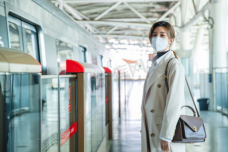 戴口罩的年轻女人站在地铁站台上