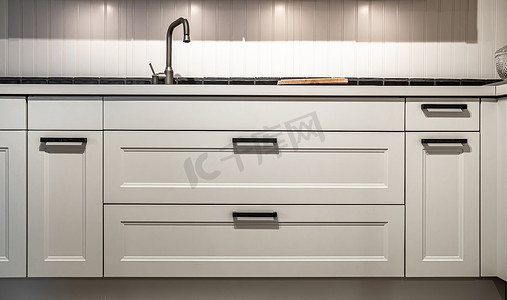 厨房的白色橱柜，室内装有金属拉链或旋钮.