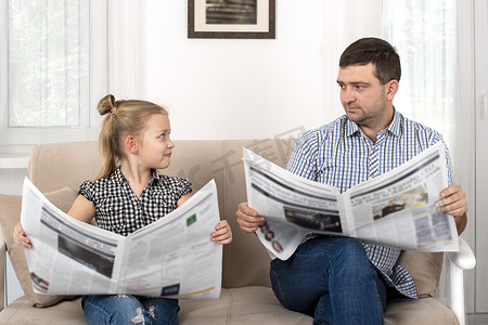 杀了一个女儿和爸爸一起呆在家里他们坐在沙发上，用同样的方式一起看报纸。女儿模仿她的父亲.