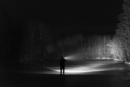晚上在森林里站在户外的人用手电筒闪亮向前。漂亮的强光束。美丽的抽象照片。平静, 和平和神秘的形象.