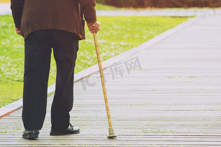 老人手杖站在人行道上，在公园内独自过马路。概念高级街对面。软聚焦